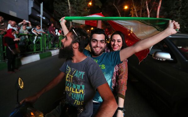 تهرانی ها در استقبال از امضای توافق هسته ای پرچم های ملی را تکان می دهند - اسپوتنیک ایران  