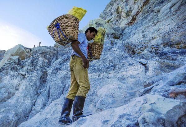 معدنچی در حال حمل سنگ گوگرد از کوه آتشفشانی کاوا ایجن در اندونزی  - اسپوتنیک ایران  