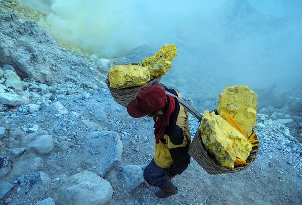 معدنچی در حال حمل سنگ گوگرد از کوه آتشفشانی کاوا ایجن در اندونزی . دستمزد معدنچیان حدود 8-7 دلار در روز است - اسپوتنیک ایران  