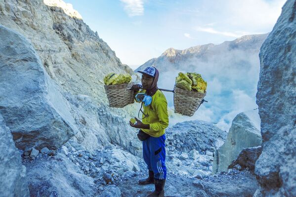 معدنچی در حال حمل سنگ گوگرد از کوه آتشفشانی کاوا ایجن در اندونزی - اسپوتنیک ایران  