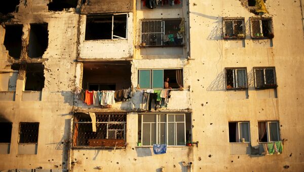 Палестинцы смотрят из дома, поврежденного израильскими обстрелами год назад, в городе Бейт-Лахия, Секторе Газа - اسپوتنیک ایران  