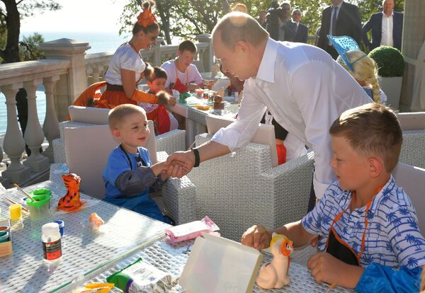 ولادیمیر پوتین رئیس جمهور روسیه در حال دیدار با کودکان خانواده‌های سیل‌زده ایرکوتسک در سوچی - اسپوتنیک ایران  