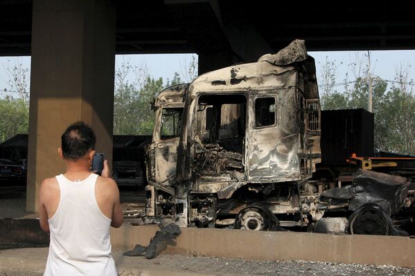 عکس گرفتن از کامیون سوخته در نتیجه وقوع انفجار در شهر تیانجین چین - اسپوتنیک ایران  