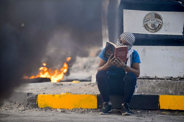 شرکت کننده در اعتراضات ضد دولتی در حال خواندن کتاب در نجف عراق - اسپوتنیک ایران  