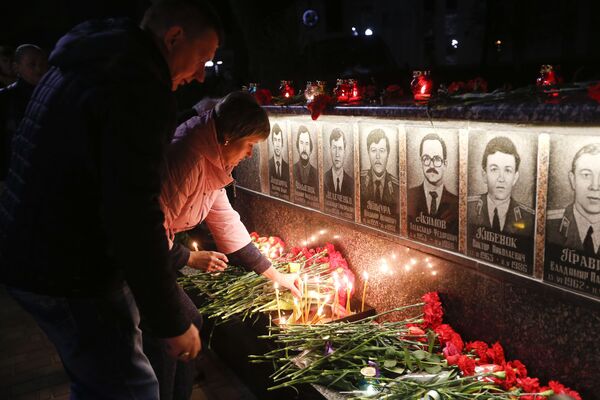 Люди возлагают цветы и зажигают свечи во время проведения акции памяти ликвидаторов и жертв аварии на Чернобыльской атомной электростанции в городе Славутич - اسپوتنیک ایران  