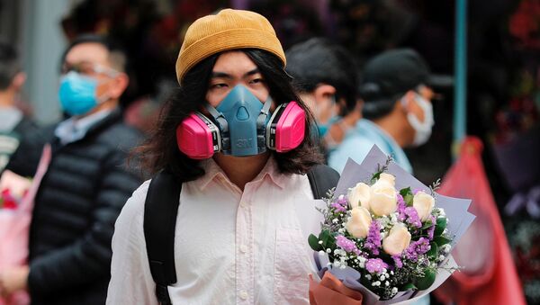 مردی با ماسک و دسته گل ولنتاین در یکی از خیابان های هنگ کنگ - اسپوتنیک ایران  