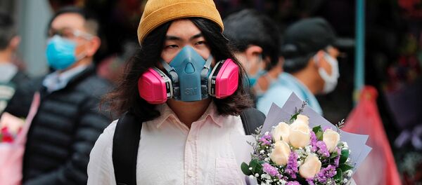 مردی با ماسک و دسته گل ولنتاین در یکی از خیابان های هنگ کنگ - اسپوتنیک ایران  