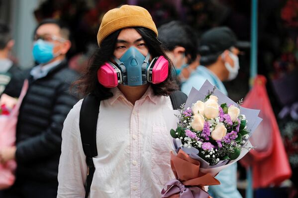مردی با ماسک و دسته گل ولنتاین در یکی از خیابان های هنگ کنگ - اسپوتنیک ایران  