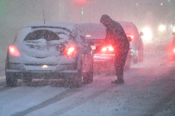 مردی در حال روبیدن برف از روی خودرو در پادولسک - اسپوتنیک ایران  