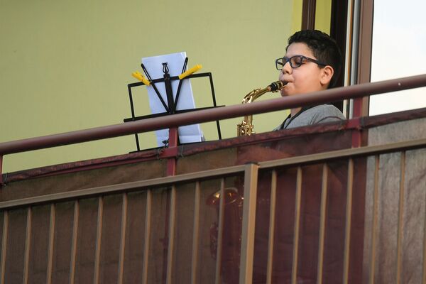 پسری مشغول نواختن ساکسیفون در بالکن خانه اش در میلان - اسپوتنیک ایران  