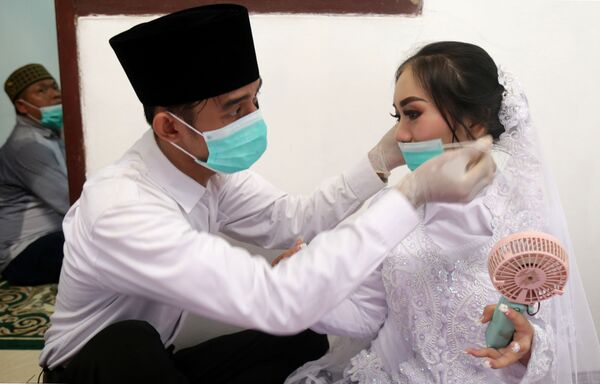 مراسم ازدواج با ماسک و دستکش سفید
 عروس و داماد در جاکارتا - اسپوتنیک ایران  