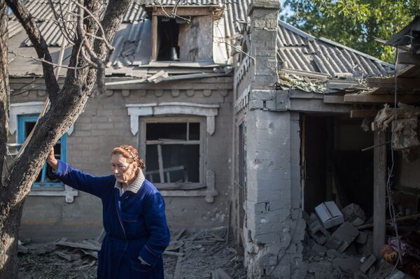زنی در کنار خانه آسیب دیده در دونتسک - اسپوتنیک ایران  