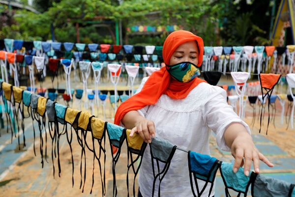 زنی با ماسک در حال درست کردن ماسک در اندونزی - اسپوتنیک ایران  