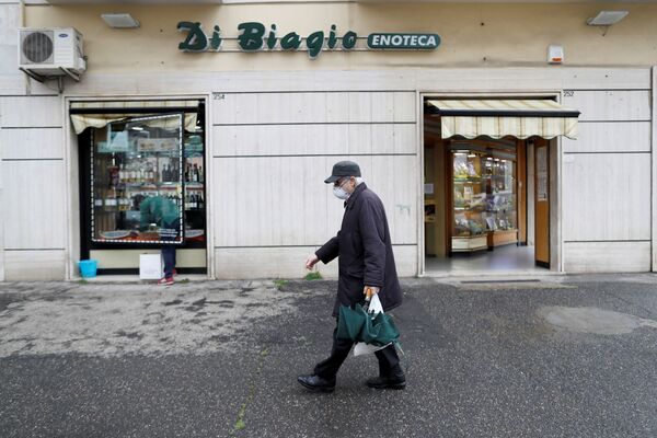 مردی با ماسک از کنار مغازه مشروب فروشی در رم عبور می کند - اسپوتنیک ایران  