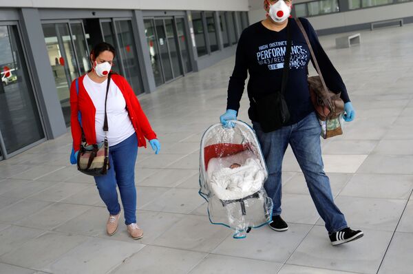 زوج با ماسک نوزاد تازه به دنیا آمده شان را به خانه می برند، اسپانیا - اسپوتنیک ایران  
