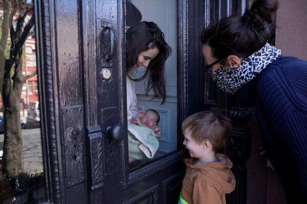 مادر کودک تازه متولد شده اش را از پشت شیشه به خانواده اش نشان می دهد، نیویورک آمریکا - اسپوتنیک ایران  