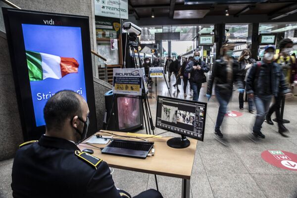نگهبان مسافران را در ایستگاه قطار در میلان کنترل می کند - اسپوتنیک ایران  