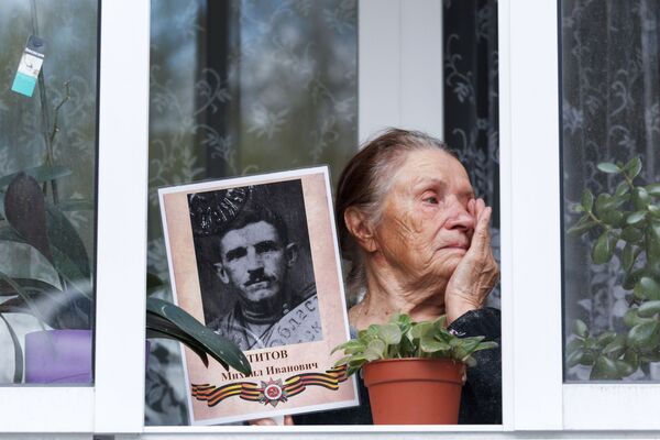 یکی از ساکنین شهر ایرکوتسک در بالکن با یک پرتره از خویشاوند خود که در جنگ جهانی دوم شرکت داشته است
 - اسپوتنیک ایران  