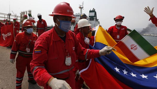 Венесуэльский работник нефтеперерабатывающего завода с флагом Ирана во время прибытия иранского танкера с топливом  - اسپوتنیک ایران  
