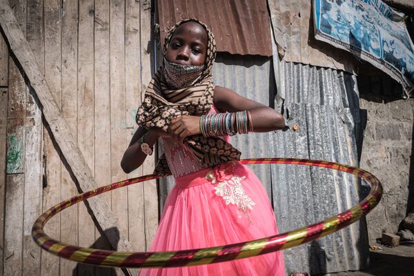 دختری یتیم در کنیا که در زمان پخش غذا با یک حلقه بازی می کند.
 - اسپوتنیک ایران  