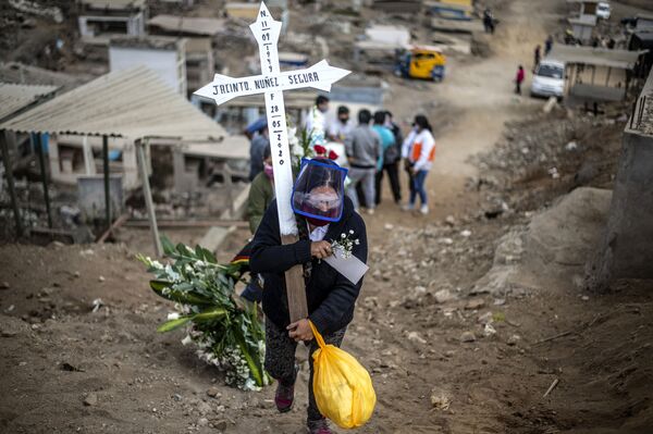 خویشاوند یک قربانی کروناویروس، صلیبی را بر روی یک گورستان در حومه لیما در کشور پرو حمل می کند
 - اسپوتنیک ایران  