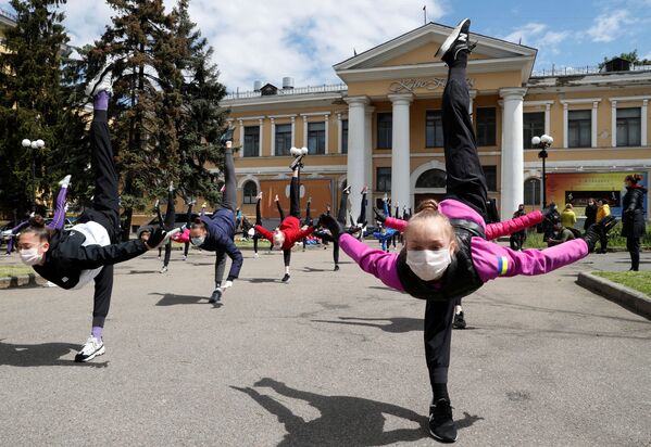 دانش آموزان مدرسه ژیمناستیک با ماسک های محافظ و دستکش در یک جلسه آموزشی در فضای باز در شهر کی یف، اوکراین تمرین می کنند
 - اسپوتنیک ایران  