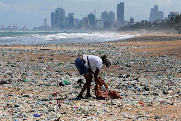 یک داوطلب زباله ها را در ساحل نزدیک یک منطقه تجاری در کلمبو، سری لانکا جمع می کند. - اسپوتنیک ایران  