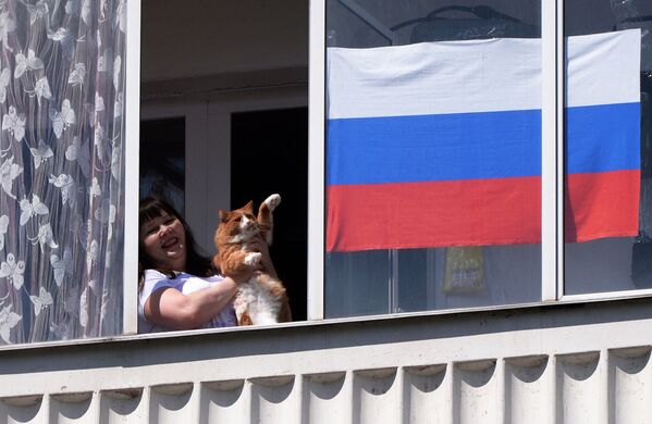 یکی از ساکنان کراسنویارسک گروه موسیقی را در روز روسیه از پنجره آپارتمان خود تماشا می کند
 - اسپوتنیک ایران  