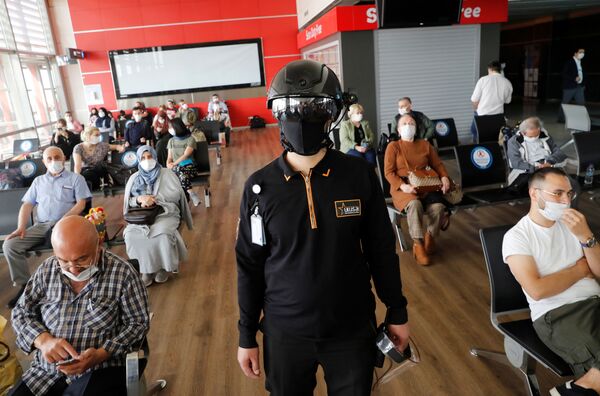 کارمند سازمان امنیت با کلاه مخصوص مراقب مسافرین در فرودگاه استانبول - اسپوتنیک ایران  