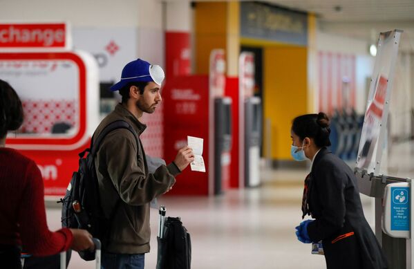 مسافر پاسپورت خود را به کارمند فرودگاهی در بریتانیا نشان می دهد - اسپوتنیک ایران  
