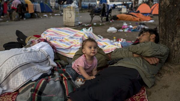 Семья мигрантов отдыхает у железнодорожного вокзала в Белграде - اسپوتنیک ایران  