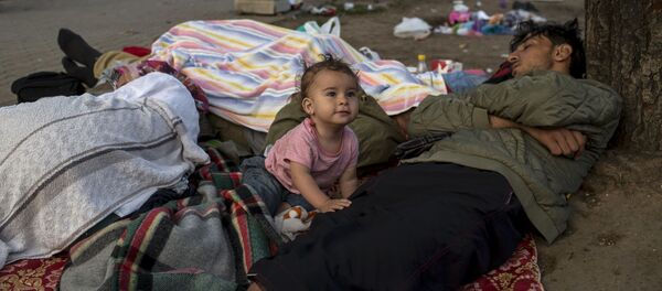 Семья мигрантов отдыхает у железнодорожного вокзала в Белграде Семья мигрантов отдыхает у железнодорожного вокзала в Белграде - اسپوتنیک ایران