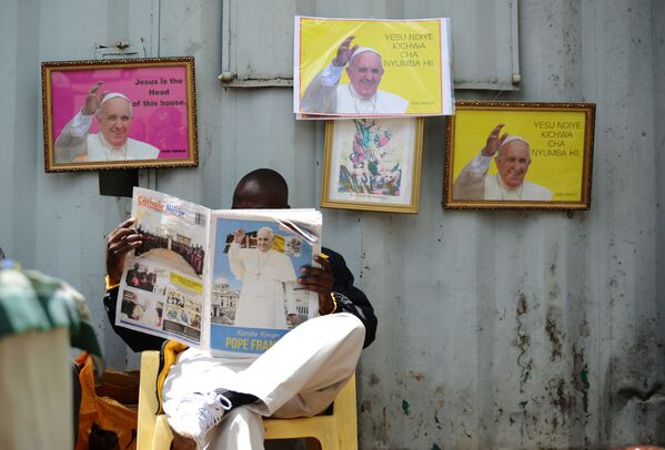 مردی در حال خواندن روزنامه در زمینه عکس های پاپ روم - اسپوتنیک ایران  
